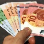 A fan of euro banknotes in various denominations held in a hand.